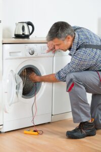 a man working on a washing machine.