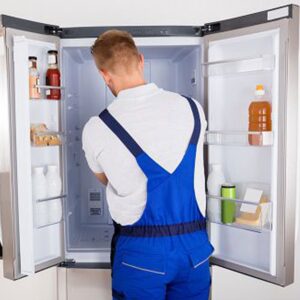 a man in overalls opening the door of a refrigerator.