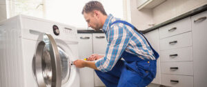 a man fixing a washing machine in a kitchen.