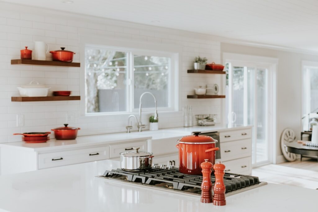 a white kitchen with red pots and pans.