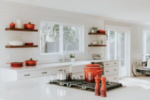 a white kitchen with red pots and pans.