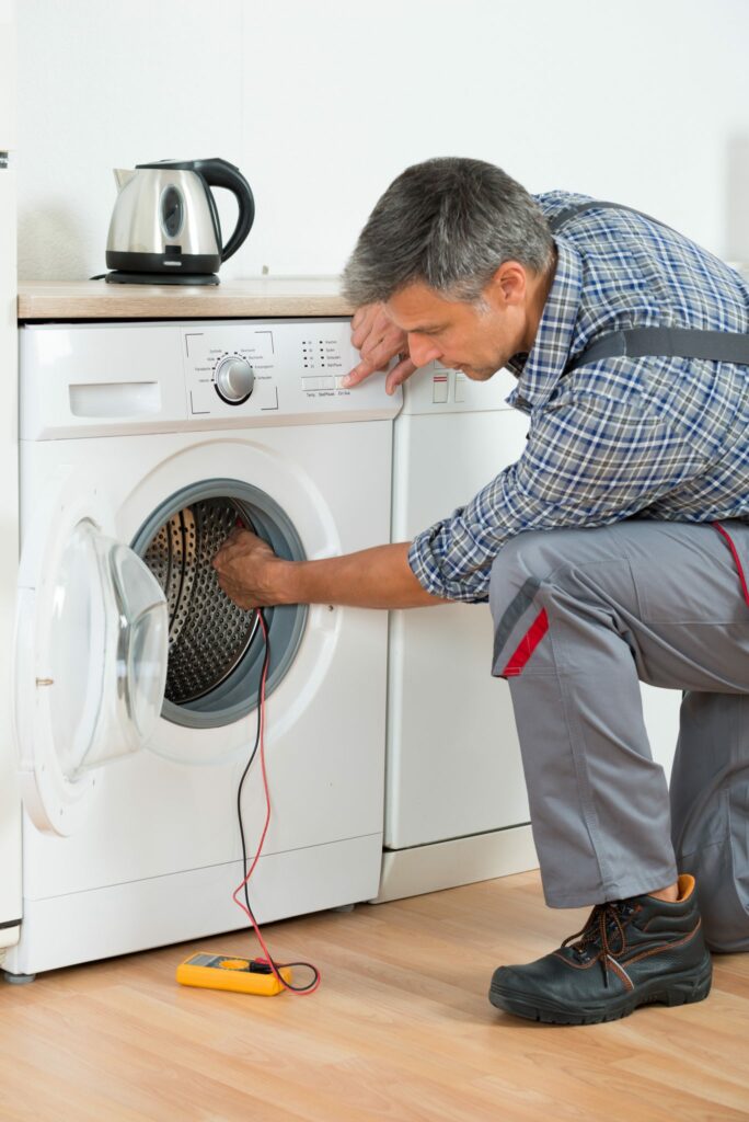 a man in overalls using a washing machine.