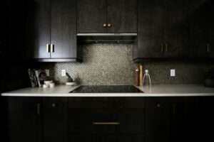 A kitchen with black cabinets and gold accents.