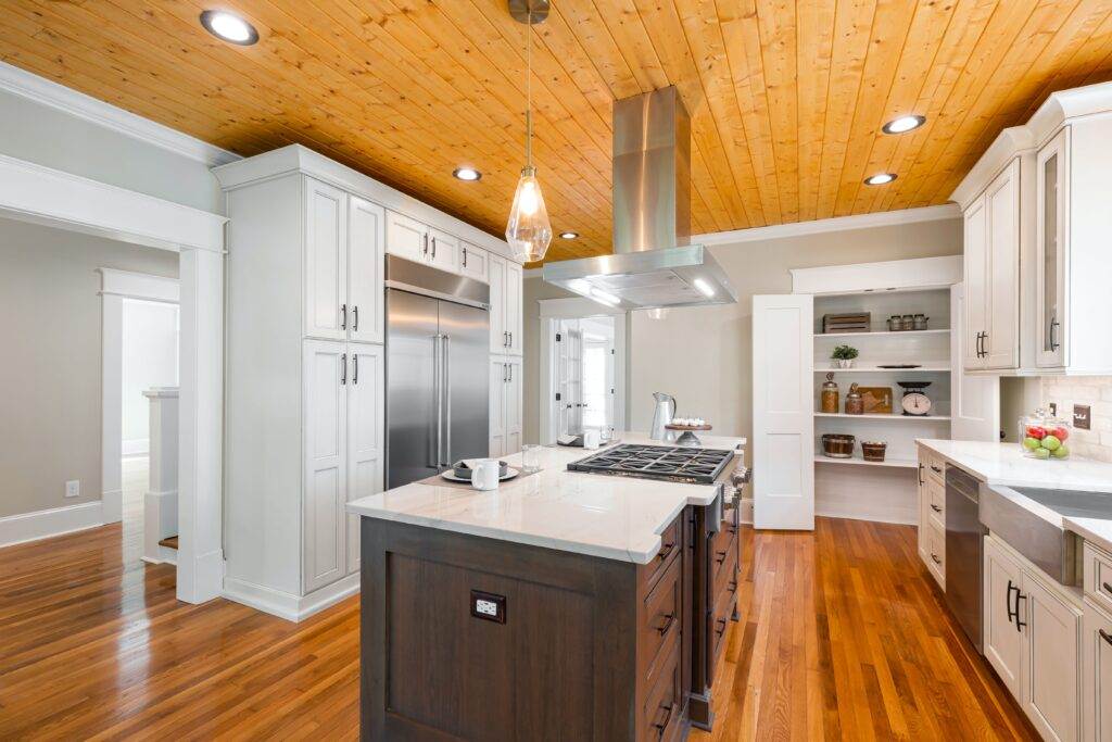 A kitchen with white cabinets and wood floors.