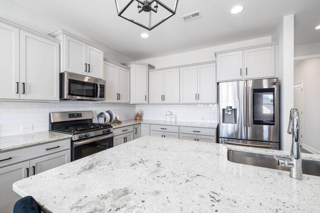 A white kitchen with granite counter tops and stainless steel appliances.