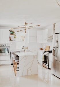 a white kitchen with marble counter tops and stainless steel appliances.