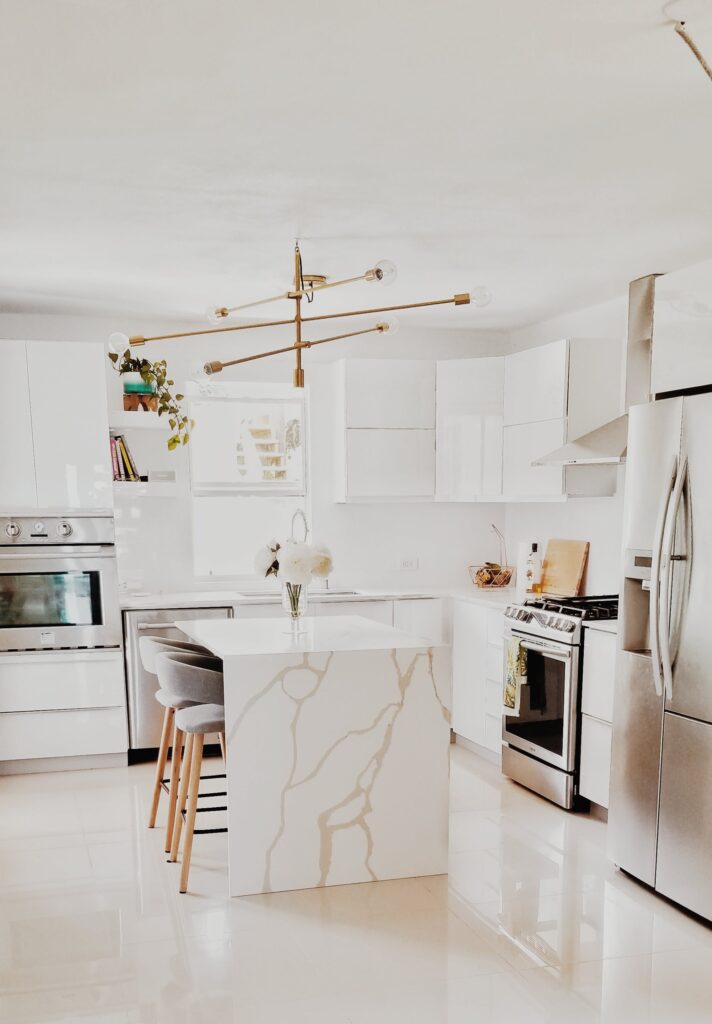 a white kitchen with marble counter tops and stainless steel appliances.