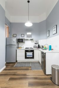 a small kitchen with white cabinets and wooden floors.