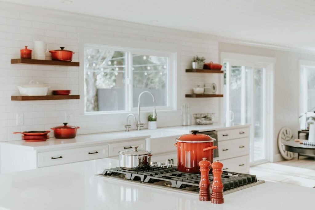 a white kitchen with red pots and pans.
