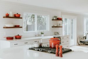 a white kitchen with red pots and pans.