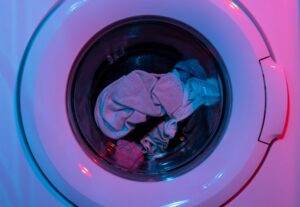 Washing machine with clothes inside, illuminated by blue and pink lights, showcasing appliance repair service theme.