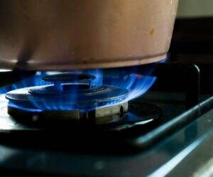 A pot on a stove with blue flames.