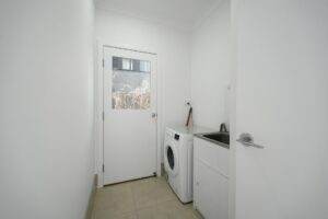 A laundry room with a washing machine and door.