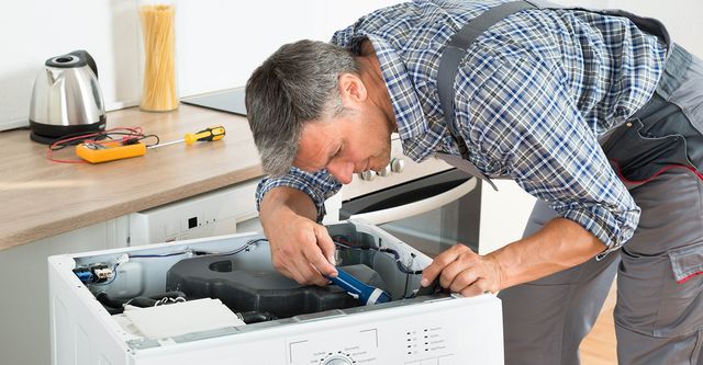 Appliance repair technician fixing washing machine