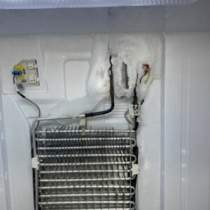 Close-up of a refrigerator interior showing frost buildup on the cooling coil and wiring, indicating a need for affordable appliance repair services.